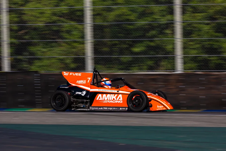 Carro de Fórmula Vee da AMIKA Racing em alta velocidade durante corrida em autódromo.