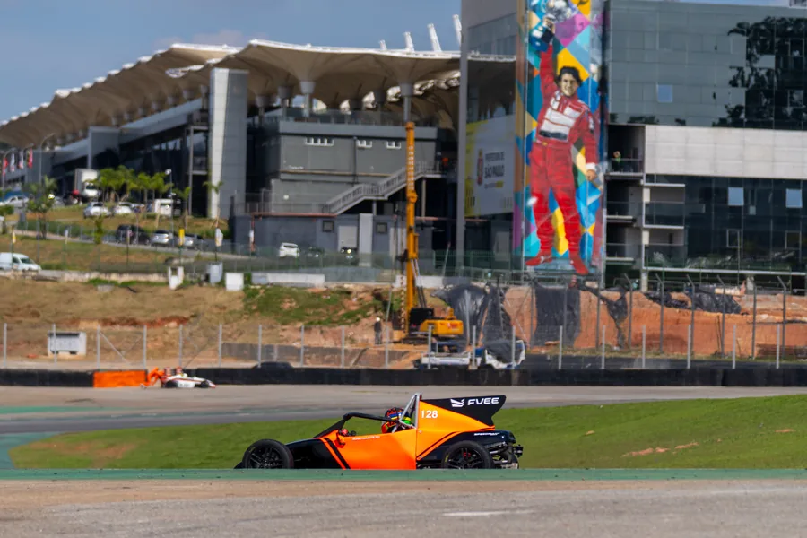 Carro de Fórmula Vee contornando uma curva no Autódromo de Interlagos, com a torre do circuito ao fundo.