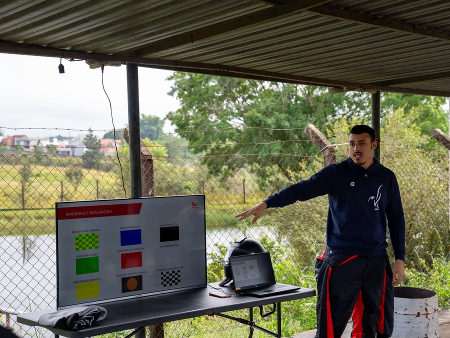 Instrutor apresenta as bandeiras de sinalização do automobilismo durante briefing antes de atividade em pista.