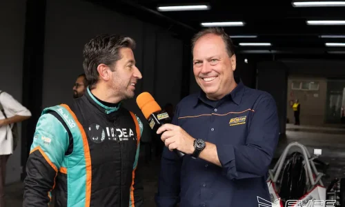 Piloto de Fórmula Vee sendo entrevistado nos boxes do autódromo após atividade em pista, com microfone e equipe ao fundo