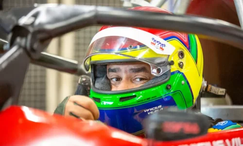 Piloto de Fórmula Vee usando capacete homologado dentro do cockpit do carro, demonstrando equipamentos de segurança obrigatórios no automobilismo.